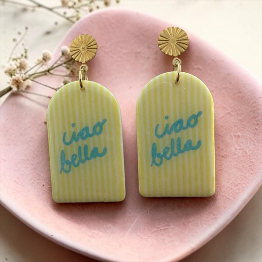 Ohrring aus Polymer Ton gelb gestreift mit Aufschrift ciao bella in blau und vergoldetem Edelstahl-Ohrstecker mit Sonnenstrahlenprägung