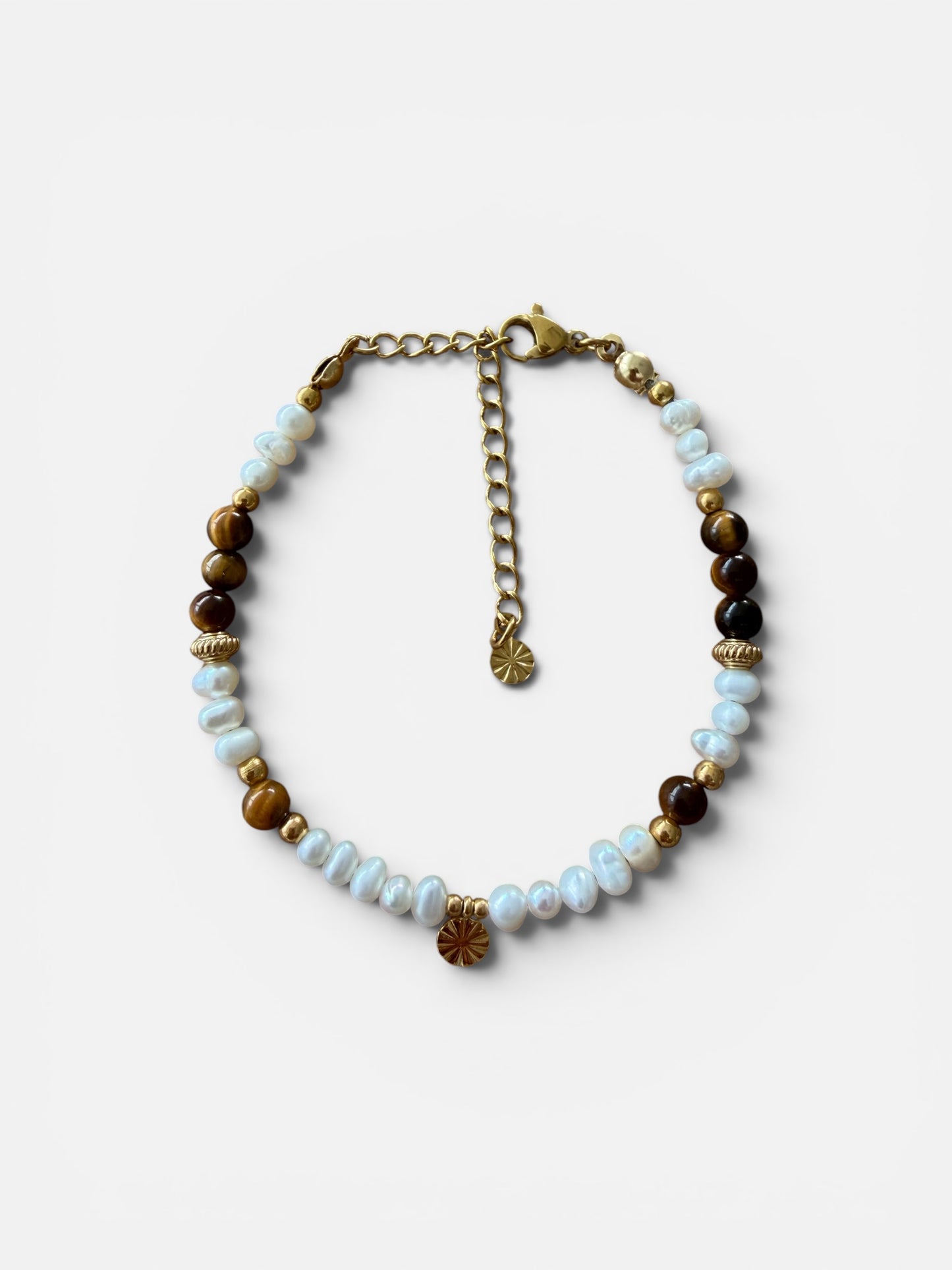 Handgefertigtes Solea Armband aus natürlichen Süsswasserperlen, Tigerauge und vergoldeten Edelstahldetails auf weissem Hintergrund. 
