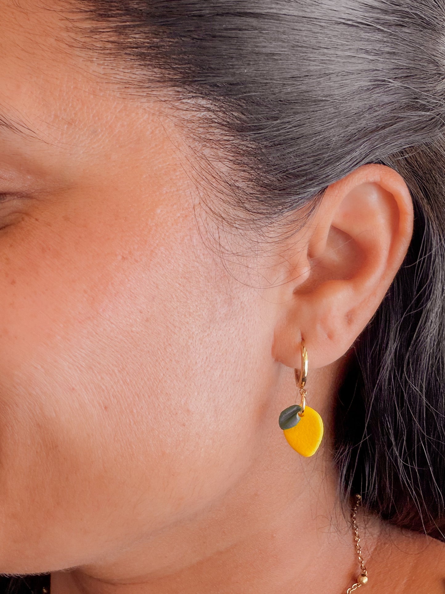 Zitronen Ohrringe aus Polymer Clay an goldener Creole getragen. 